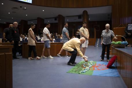 Un hombre deja unas flores sobre una bandera del pueblo gitano durante el acto conmemorativo por el Samudaripen